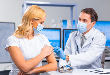 Professional doctor makes a coronavirus vaccine using a syringe and hypodermic needle. Professional medical worker and patient at the hospital office. Vaccination and safety.