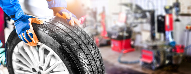 Auto mechanic working in garage and changing wheel alloy tire. © Milan