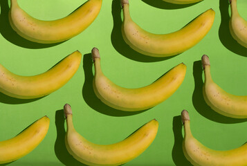 Creative yellow bananas pattern on green background.