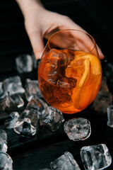 orange coctail with ice in hand