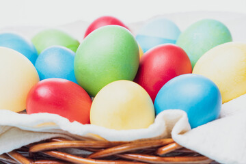 Fototapeta na wymiar basket with colorful Easter eggs on a blue wooden background, selective focus, tinted image