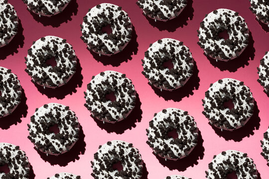 White donuts with black crumb on a pink background