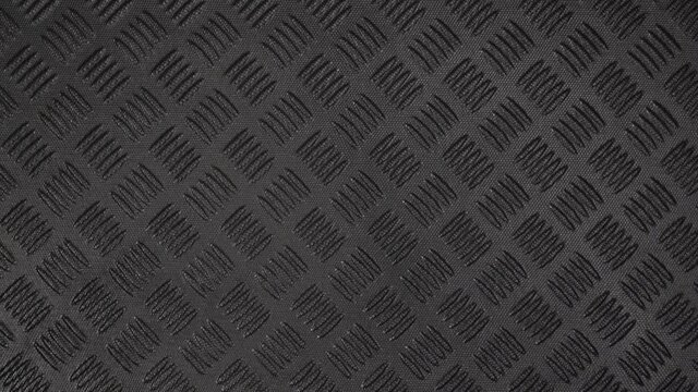 Closeup top view flatlay 4k stock video footage of texture of black protective hdpe rug or mat for boot of car