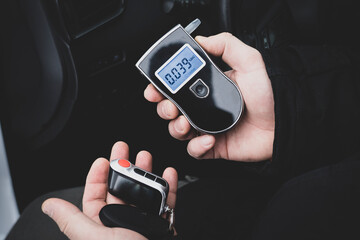 a man with a breathalyzer in the car, testing for alcohol and drug intoxication of the driver,...