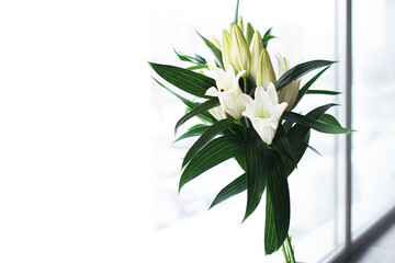 Beautiful lilies bouquet on light brown background, closeup view. Space for text