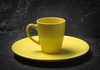 empty yellow plate and tea cup on black textured background