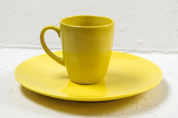 an empty yellow plate and cup on a white textured background