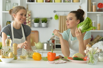 Obraz na płótnie Canvas Portrait of beautiful teenagers cooking in kitchen