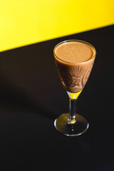 Liquor in a stemmed glass on the yellow and black background. Background with copy space. Trend color of the year 2021