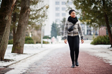 African woman wear in black scarf walks on the path in winter day at Europe.