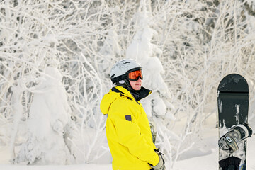 Cute young woman snowboarder in a bright overalls in a sports helmet and ski goggles on the...