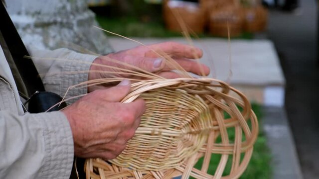 Old man's hands weaving a basket