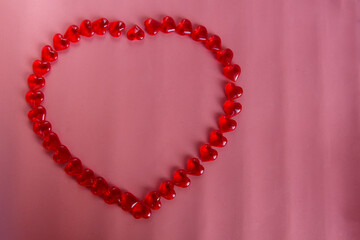 Red small hearts lined the outline of a large heart on a pink background. Place for text