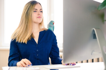 beautiful young business woman using computer at home with parrot © Gita