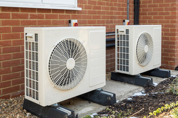 Air source heat pumps installed on the outside of a modern house