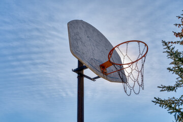 Outdoor basketball hoop with sun and clouds