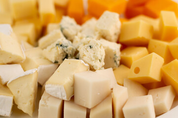 Background in yellow tones from sliced ​​pieces of different types of cheese: Camembert, Roquefort, Cheder, Gouda.