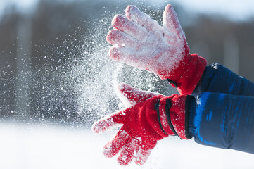 Hands wearing in the red gloves shake out a snow