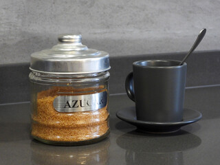 A cup of coffee and a pot of brown sugar