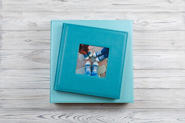Blue leather photo album on cardboard box.
family photo book with leather cover in gift box with ribbon.
stylish box with photoalbum on wooden background. square photobook with space for text