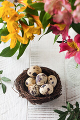 Quail eggs in a nest on a background of flowers. The concept of Easter, spring greeting card.