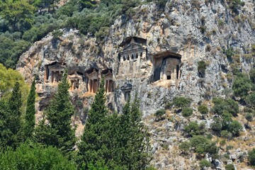 Fototapeta na wymiar Amazing view of the Lycian tombs carved into the rock on the Dalyan River, ancient Caunos town, Turkey, Mugla. Turkish famous historical landmark