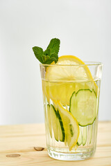 glass of refreshing lemonade with cucumber and lemon on a wooden table