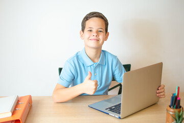 Young boy smiling and watching laptop in the classroom.A young boy student typing computer for learning online at his home.