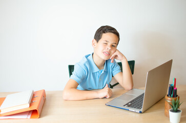 Young boy smiling and watching laptop in the classroom.A young boy student typing computer for learning online at his home.