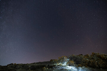 Fototapeta na wymiar Beautiful winter dark starry sky over the rock. Night photography, astronomical background. 