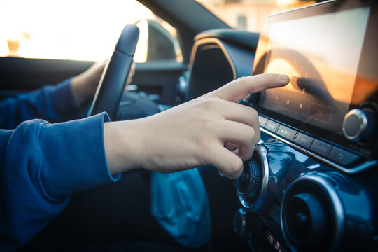 Teen drive a car and use infotainment. Young man reading messages and make phone call while driving. Dangerous behavior, accident risk. Danger, transgression, youth, distraction concept. Focus on hand