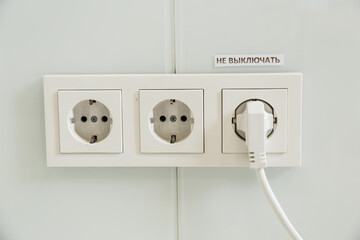 several plastic socket, white, mounted on a gray wall. one outlet in use