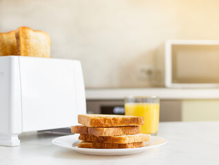European breakfast in the kitchen in the morning. White electric bread toaster with orange juice...