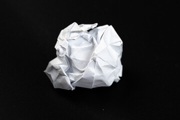 A crumpled paper ball in a black background