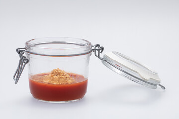 Clear glass jar with tomato gel on white background