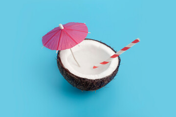 Tropical summer and vacation minimal concept. Coconut on a blue background with a cocktail straw. Vacation, travel, beach idea.