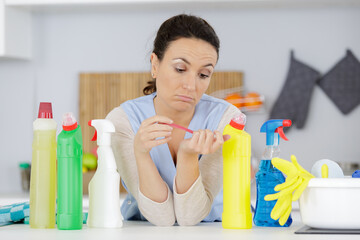 tired young woman on kitchen with bunch of cleaning products