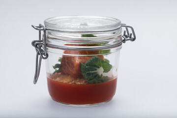 Clear glass jar with tomato gel, baked salmon and pak-choi leaves
