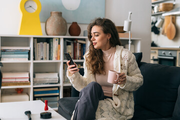 woman drinking morning coffee and using smartphone at her home
