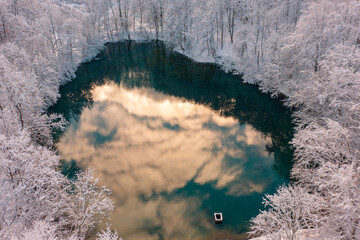 Szilvásvárad, Hungary - Aerial view of the famous Upper lake also known as Sipovics tengerszem with crystal clear turquoise water. Snowy winter forest.