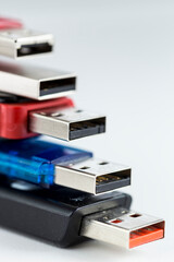 Five colorful usb flash drives on top of one another, against a white background