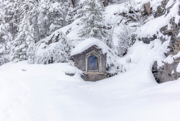 Fototapeta na wymiar A small shrine during the ski touring in the mountains and forest above Alvaneu in the Swiss Alps