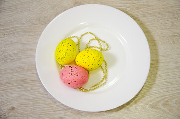 colorful eggs for Easter that lie on a white plate and light with sparkles