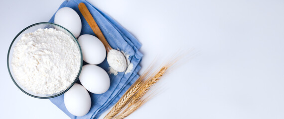 Ingredients for dough preparation: flour and eggs on white background. Close-up. Top view. Copy space. Banner.