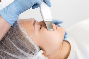 Naklejka premium Cosmetologist cleans the face of a girl close-up