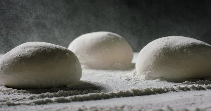 Flour dust falling on dough formed into loafs of bread. Sifting flour in a bakery show. Making of bread. Food and drink close up 4k footage