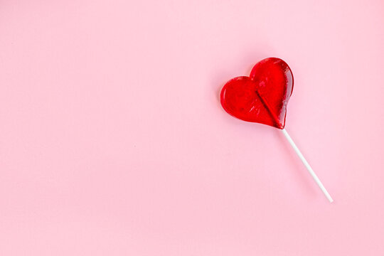 Heart shaped lollipop on pink background