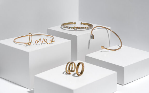 Golden bracelets and rings on white boxes with copy space
