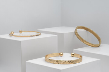Three modern golden bracelets on white boxes with copy space