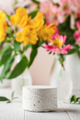 Empty concrete podium for your product presentation with flowers on the background in a spring mood.